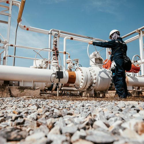 Production operator opening ball valve at pipeline oil and gas wellhead remote platform to control gases and crude oil process petroleum industry.